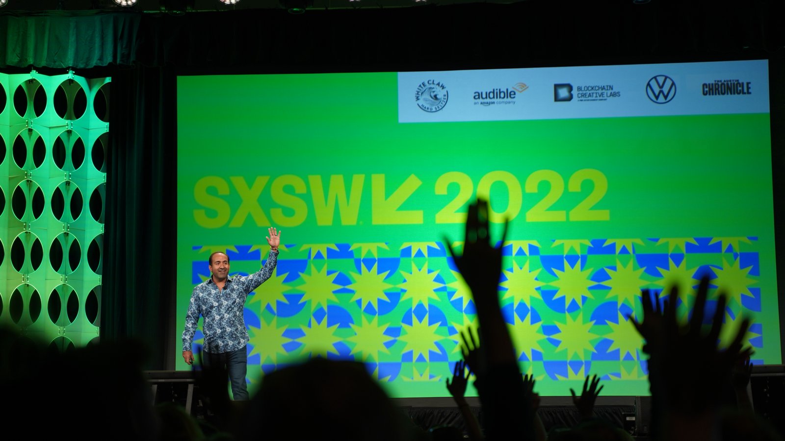 A packed room with hands raised at a Non-Obvious keynote