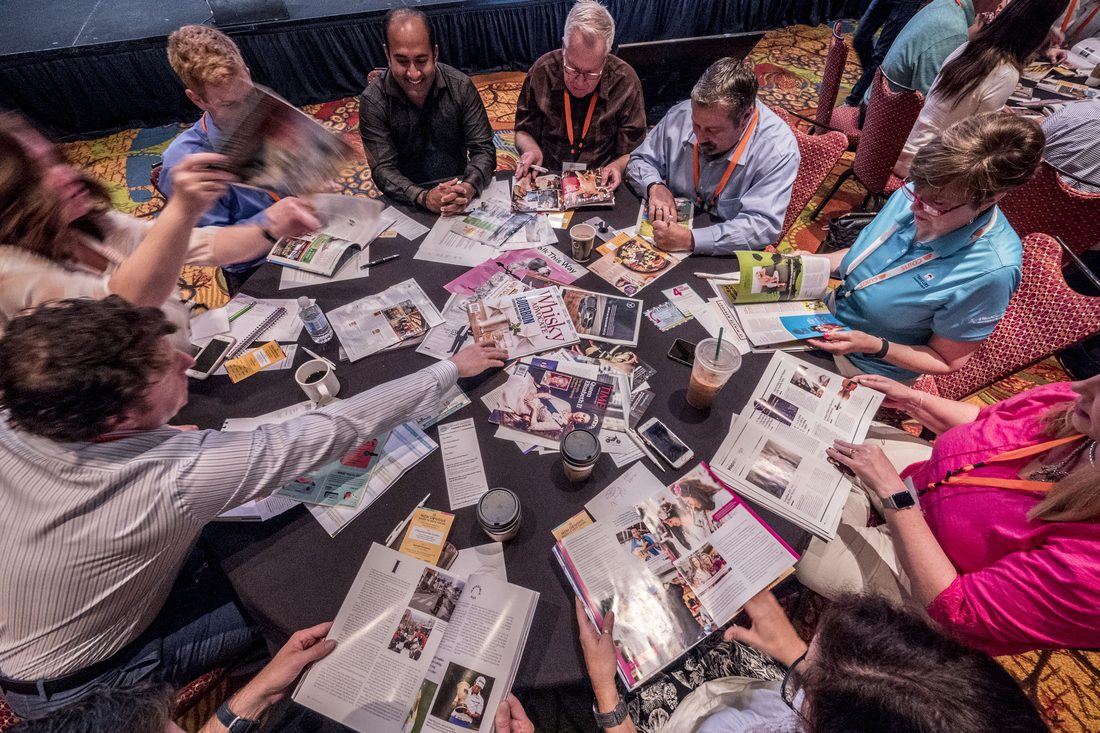 Workshop participants around a table using magazines for the Haystack Method trend curation activity
